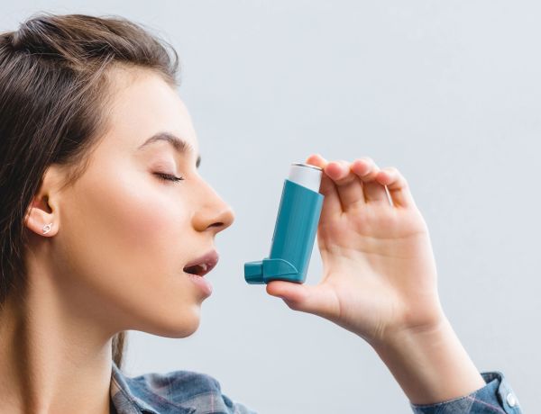 Junge Frau benutzt einen Asthma-Inhalator gegen Atembeschwerden.