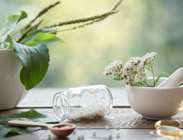Globuli-Fläschchen und Blüten als Symbol für Homöopathie.