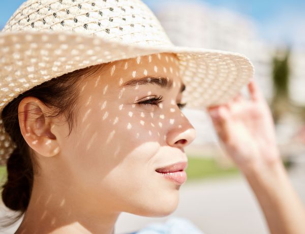 Frau mit Sonnenhut schaut in die Sonne
