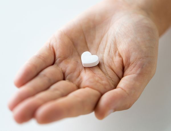 Ausgestreckte Hand mit einer Süßigkeit in Herzform.