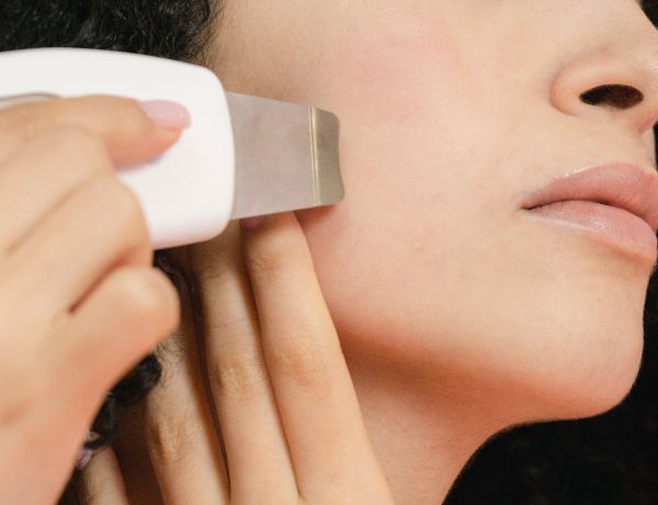 Frau hält ein medizinisches Gerät an die Wange für eine apparative Therapie.