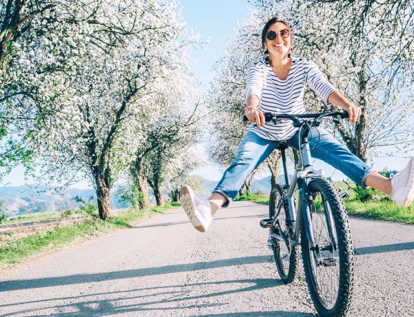 Frau fährt mit dem Fahrrad auf einem Weg im Grünen