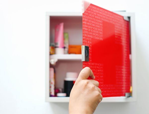 Hand öffnet roten Medizinschrank mit Arzneimitteln
