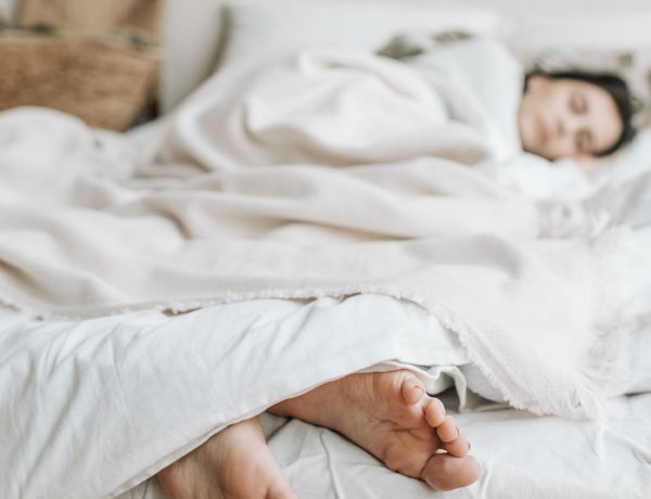 Mutter und Kind liegen schlafend nebeneinander in einem weißen Bett.