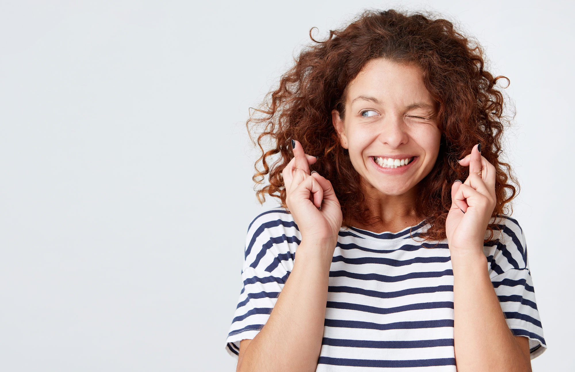 Junge Frau mit Locken und gestreiftem Shirt lächelt in die Kamera.
