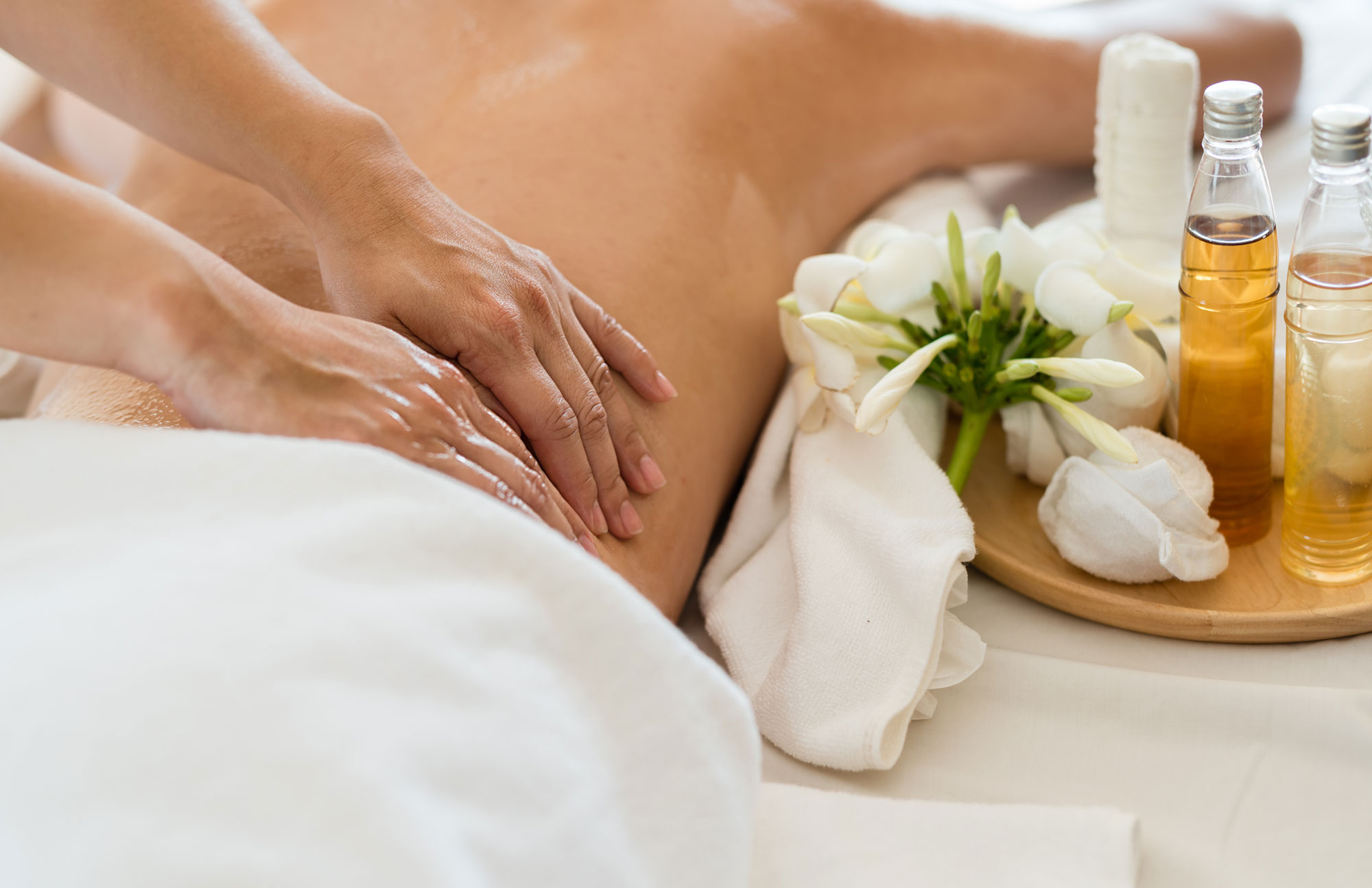 Frau liegt auf dem Bauch und erhält eine Rückenmassage mit Öl.