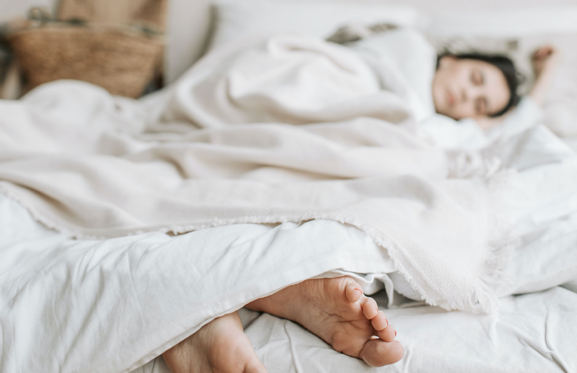Mutter und Kind liegen schlafend nebeneinander in einem weißen Bett.